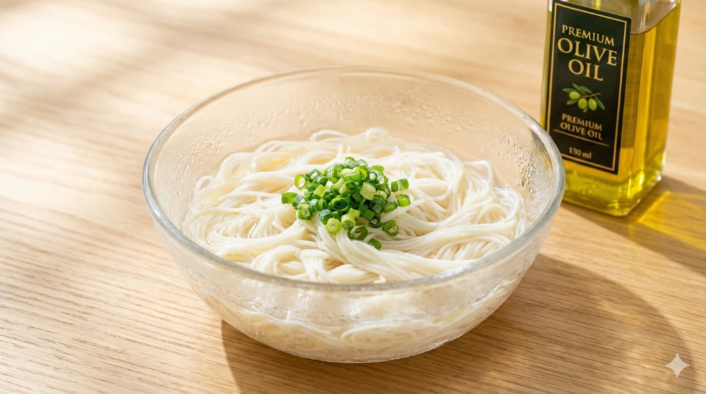 ガラス鉢に盛った生そうめんと薬味のねぎ、オリーブオイルの瓶