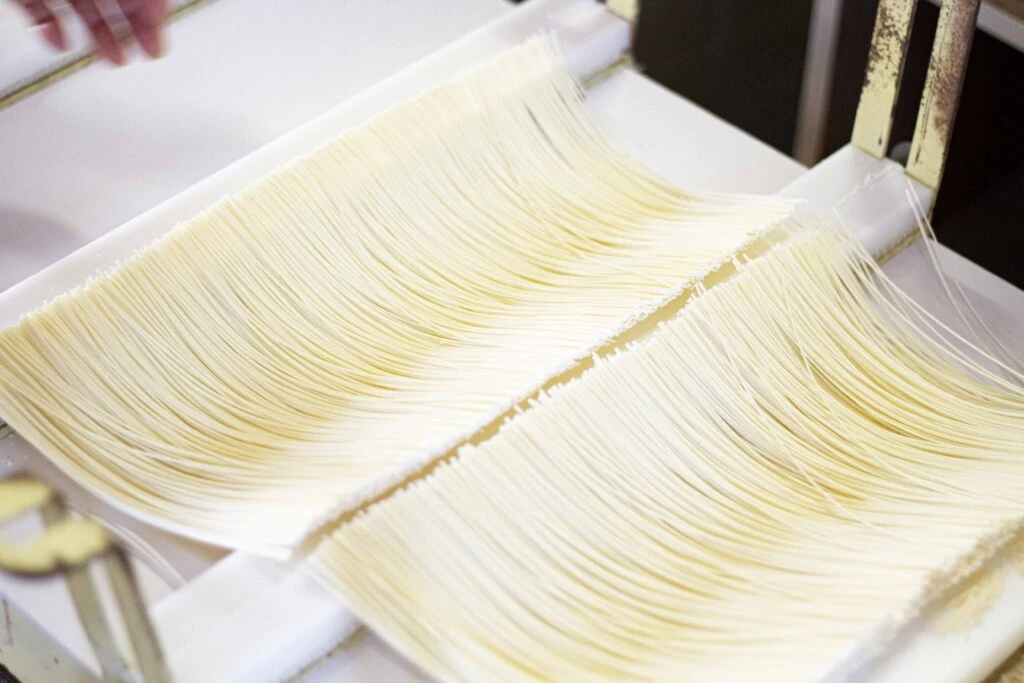 マルカツ製麺所で細く延ばされトレーに並ぶ手延べそうめんの麺
